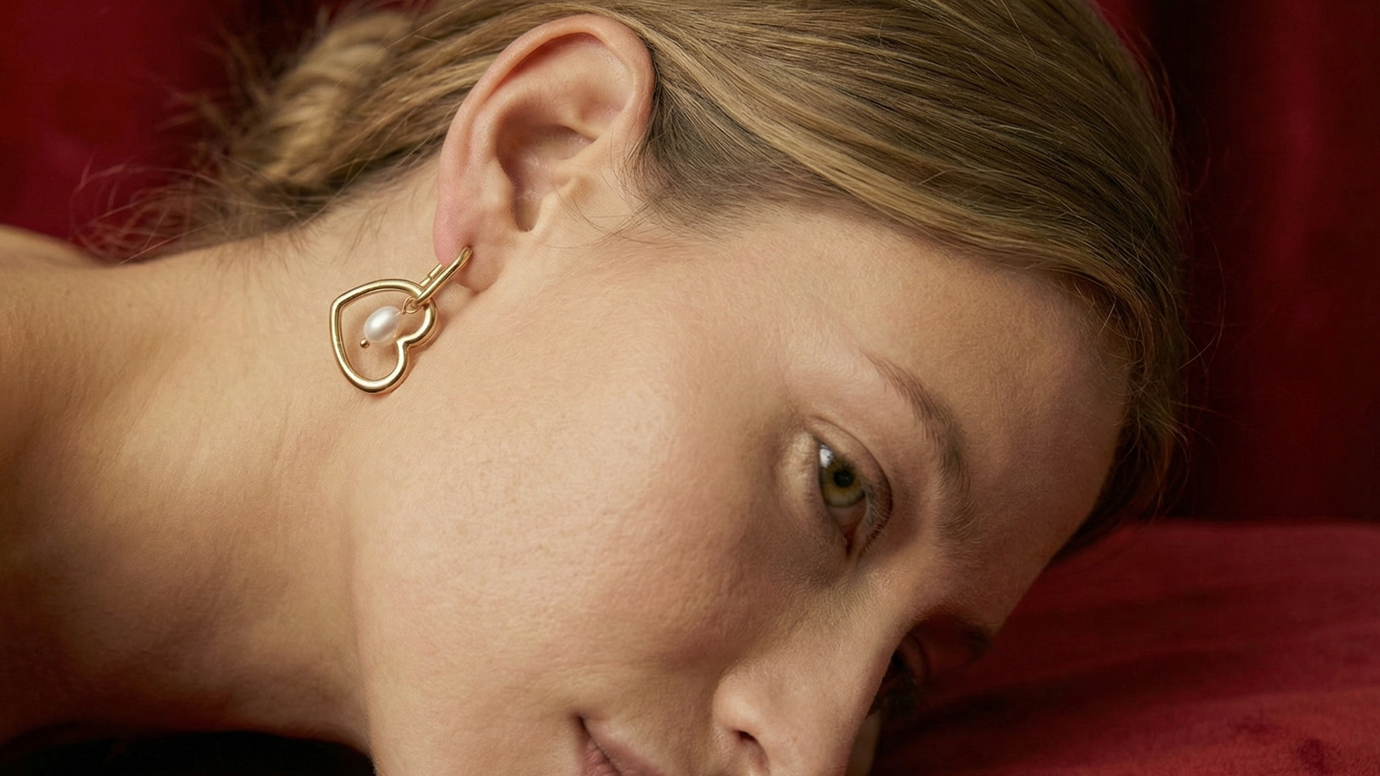 Woman wearing a gold earring on a red background