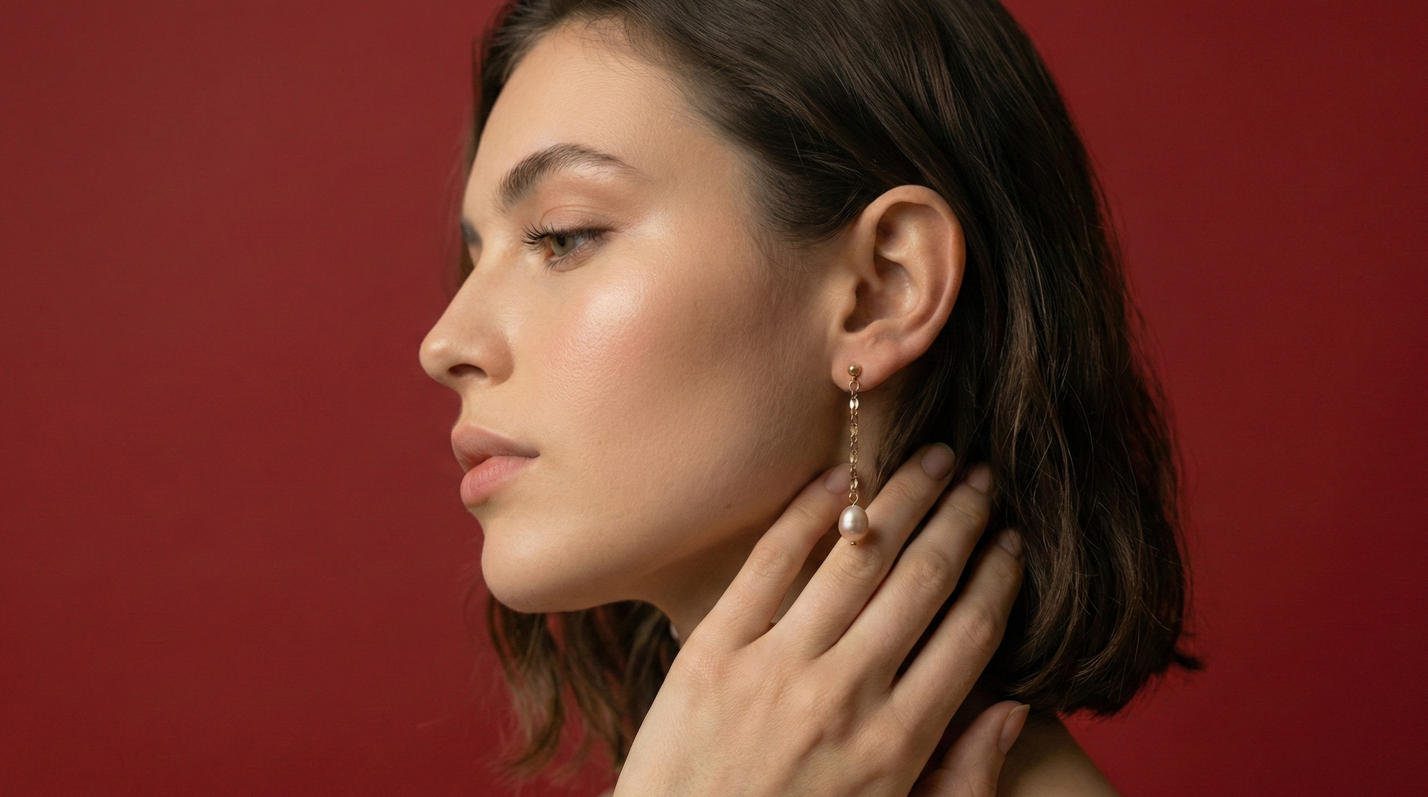 Woman wearing earrings against a red background