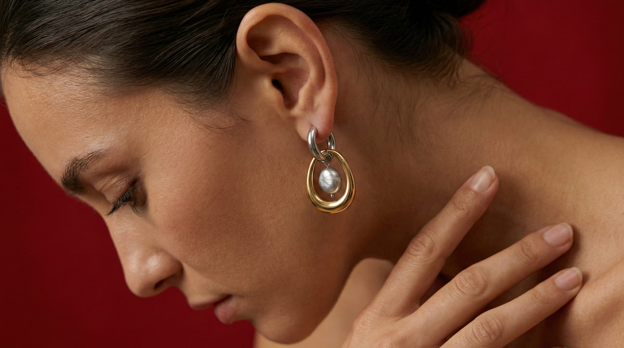 Close-up of a woman wearing gold earrings with a red background