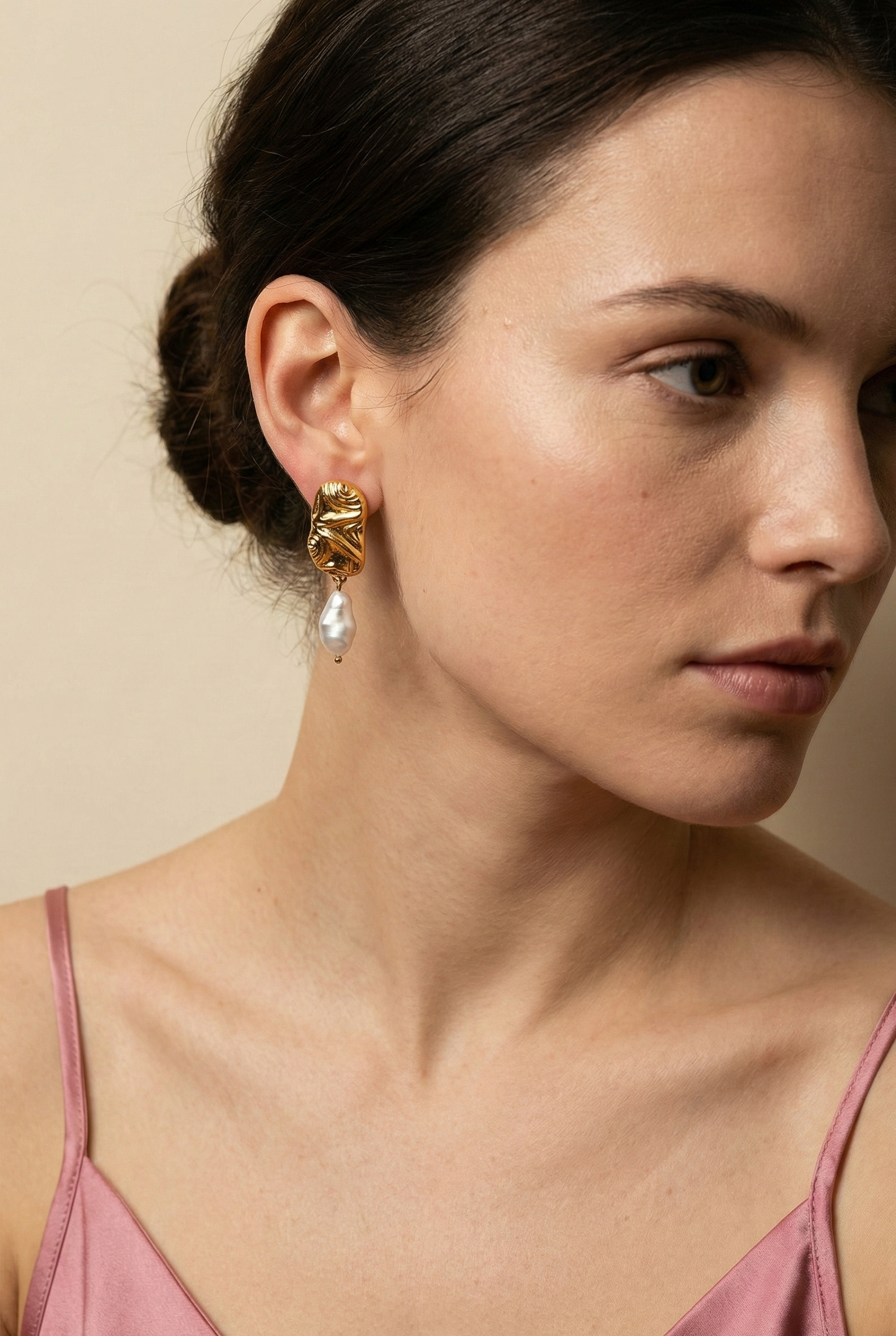 Close-up of an european model wearing sculptured aztec organic 18k gold earrings with japanese keshi pearls