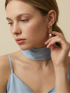 18k gold plated chain link earrings with genuine white freshwater pearls. Model wears a blue silk top, showcasing the earring's drape and classic pearl luster.